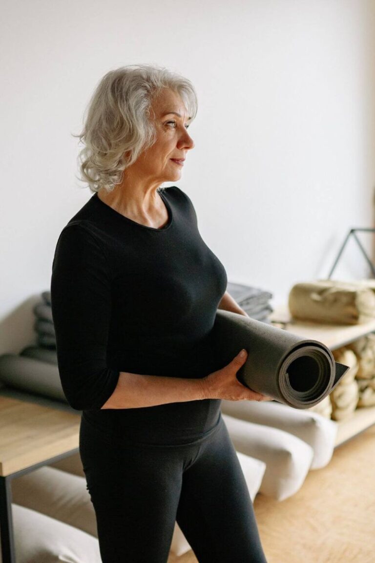 woman holding a yoga mat ready to start exercising after a hysterectomy