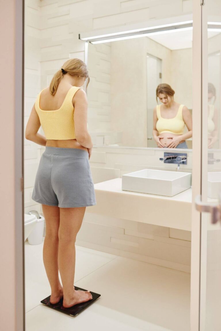 Woman on a scale wondering why she faces a weight loss plateau