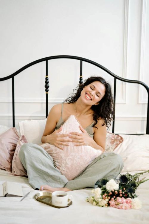 happy woman sitting bed relieved from vulvar irritation and redness